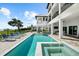 Backyard featuring a modern pool, hot tub, and lush landscaping with views of the water at 110 Carlyle Dr, Palm Harbor, FL 34683
