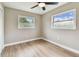 Bright bedroom featuring light walls, wood-look flooring, two windows, and a modern ceiling fan at 1110 Canal St, Ruskin, FL 33570