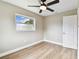 Neutrally painted bedroom with ceiling fan, wood-look floors and a large window showing the outside view at 1110 Canal St, Ruskin, FL 33570
