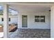 Covered front porch featuring tile flooring, a green entry door, and ample space for relaxation at 1110 Canal St, Ruskin, FL 33570
