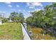 Waterfront view showcasing serene canal reflecting the lush greenery with a concrete retaining wall on the property line at 1110 Canal St, Ruskin, FL 33570