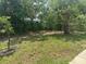 A shady backyard with a few trees, a chainlink fence, and patchy grass in need of landscaping at 116 Cranbrooke Dr, Seffner, FL 33584