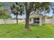 Landscaped backyard featuring green lawn, shade trees, and a covered patio seating area at 11728 Crest Creek Dr, Riverview, FL 33569
