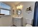 Bathroom vanity with grey cabinet and light toned wall with round mirror and decorative accents at 11728 Crest Creek Dr, Riverview, FL 33569