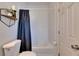 A bathroom featuring a white tiled bathtub with a blue shower curtain, toilet, and decorative shelf at 11728 Crest Creek Dr, Riverview, FL 33569