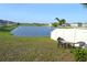 Backyard view with serene lake view, enclosed by a white fence, and furnished with a table and chairs at 16725 Delia St, Wimauma, FL 33598