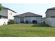Backyard featuring a sliding glass door, patio, lush grass, and partial fence, providing privacy at 16725 Delia St, Wimauma, FL 33598