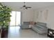 Bright living room with gray sofa, ceiling fan, and sliding glass doors at 16725 Delia St, Wimauma, FL 33598
