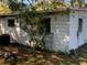 View of the back of the house with visible siding, trees and overgrown vegetation at 1716 Lancelot Loop, Tampa, FL 33619