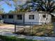 Exterior angle view of a white single-story home, showcasing the front yard with chain-link fence at 1716 Lancelot Loop, Tampa, FL 33619