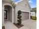 Charming home exterior featuring a manicured spiral topiary and a two-car garage at 1767 Tonka Ter, Wesley Chapel, FL 33543