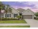 Beautiful single-story home featuring manicured lawn, attached two-car garage, and lush, tropical landscaping at 1767 Tonka Ter, Wesley Chapel, FL 33543