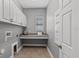 Laundry room with granite countertop, overhead cabinets, tile flooring, and utility sink at 1767 Tonka Ter, Wesley Chapel, FL 33543