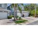 Exterior of townhomes featuring attached garages, tropical landscaping, and lush lawns at 18148 Nassau Point Dr, Tampa, FL 33647