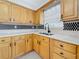 Kitchen featuring wooden cabinets, stainless steel sink and faucet, and decorative backsplash at 1921 Ridgewood Dr, Clearwater, FL 33763