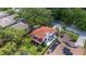 Aerial view of a charming home featuring a red roof, screened lanai, lush lawn, and solar panels at 2015 Long Branch Ln, Clearwater, FL 33760