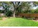 Well-maintained backyard with lush green grass, mature trees, and a wooden fence for privacy at 2015 Long Branch Ln, Clearwater, FL 33760