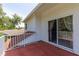 Balcony with sliding glass door entrance, white railing, and red painted flooring at 2015 Long Branch Ln, Clearwater, FL 33760
