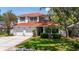 Charming two-story home boasts a red roof, a two-car garage, and a well-manicured lawn surrounded by mature trees at 2015 Long Branch Ln, Clearwater, FL 33760