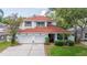 Charming two-story home boasts a red roof, a two-car garage, and a well-manicured lawn surrounded by mature trees at 2015 Long Branch Ln, Clearwater, FL 33760