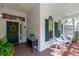 Charming front porch with a brick floor, wicker furniture, and green accents creating a welcoming and cozy entrance at 2015 Long Branch Ln, Clearwater, FL 33760