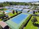 Aerial view of a community with mature trees, pool, and tennis court on a sunny day at 2131 Ridge S Rd # 3, Largo, FL 33778