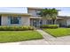 Home exterior with blue shutters, lush green lawn, and mature tropical trees in the front of the property at 2131 Ridge S Rd # 3, Largo, FL 33778
