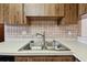 Close-up of a kitchen sink with double basins and tile backsplash at 2131 Ridge S Rd # 3, Largo, FL 33778