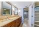 Bathroom featuring dual sinks, granite counters, wood cabinets, tiled floors, and a glass enclosed shower at 240 Sand Key Estates Dr # 222, Clearwater, FL 33767