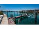 Waterfront view of a wooden dock and boat lift on a sunny day with other homes in the background at 240 Sand Key Estates Dr # 222, Clearwater, FL 33767