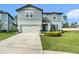 Charming two-story home with light blue siding, a well-manicured lawn, and an attached two-car garage at 30572 Thunderbird Dr, Wesley Chapel, FL 33545