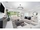 Bright living room featuring tile floors, neutral furniture, a modern chandelier, and large windows for ample natural light at 30572 Thunderbird Dr, Wesley Chapel, FL 33545