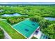 Aerial view of the green tennis courts near a beautiful pond surrounded by lush green foliage at 3229 40Th S Ln # C, St Petersburg, FL 33711