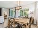 Bright dining area with rustic wood table, designer light fixture, and view to outdoor patio at 32825 Sand Creek Dr, Wesley Chapel, FL 33543