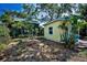 View of the backyard featuring a yellow outbuilding and lush tropical landscaping at 420 Roanoke St, Dunedin, FL 34698