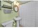A well-lit bathroom featuring a pedestal sink, toilet, and shower with a white curtain at 420 Roanoke St, Dunedin, FL 34698