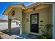 Inviting front door with decorative glass, a small porch, and a carport adorned with a sun decoration at 420 Roanoke St, Dunedin, FL 34698