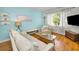Well-lit living room featuring hardwood floors, a large window, and stylish decor at 420 Roanoke St, Dunedin, FL 34698