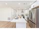 Bright, white kitchen with stainless steel appliances and central island featuring a quartz countertop at 4812 El Capistrano Dr, Tampa, FL 33634