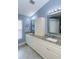 Bathroom featuring double granite vanity, stylish mirrors, ample storage, and blue wall color at 5619 Essex Ct, Palm Harbor, FL 34685
