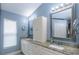 Bathroom featuring double granite vanity, stylish mirrors, ample storage, and blue wall color at 5619 Essex Ct, Palm Harbor, FL 34685
