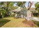 Charming single-story home with a three-car garage, lush lawn, mature trees, and tropical landscaping at 5619 Essex Ct, Palm Harbor, FL 34685