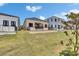 A well-maintained backyard showcases modern home design with green lawn and minimalist landscape against a blue sky at 6532 Simone Shores Cir, Apollo Beach, FL 33572