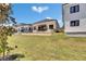 View of a modern home's backyard with a well-manicured lawn and neighboring houses, set against a blue sky at 6532 Simone Shores Cir, Apollo Beach, FL 33572