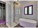 Modern bathroom boasts soaking tub, glass shower, and sleek fixtures with stylish purple accent lighting around the window at 6532 Simone Shores Cir, Apollo Beach, FL 33572