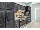 Close up shot of a kitchen featuring stainless steel appliances, decorative backsplash and dark cabinetry at 7461 Pescador Pl, Seminole, FL 33772