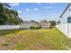 Spacious backyard with a manicured lawn, bordered by a white fence and lush landscaping at 807 Illinois Ave, Palm Harbor, FL 34683