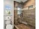 Modern bathroom with glass shower, wood-look tile, mosaic accent, and natural light from a window at 807 Illinois Ave, Palm Harbor, FL 34683
