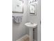 Cozy half-bathroom featuring a pedestal sink, starfish art, and light grey walls at 8415 Edgewater Place Blvd, Tampa, FL 33615