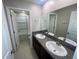 Bathroom with double sink vanity, granite countertop, and tiled shower at 9520 Lemon Drop Loop, Sun City Center, FL 33573